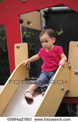 Stock Image - little girl going down slide. Fotosearch