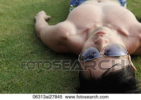 man laying on grass wearing sunglasses View Large Photo Image Stock Photography - man laying on grass wearing sunglasses. Fotosearch