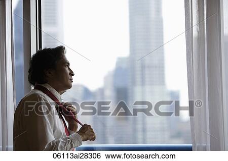 Man looking out of window and tying his tie. View Large Photo Image Stock Photograph - Man looking out of window and tying his tie.. Fotosearch