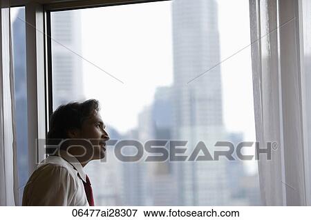 man standing by window looking up at buildings View Large Photo Image Stock Photo - man standing by window looking up at buildings. Fotosearch