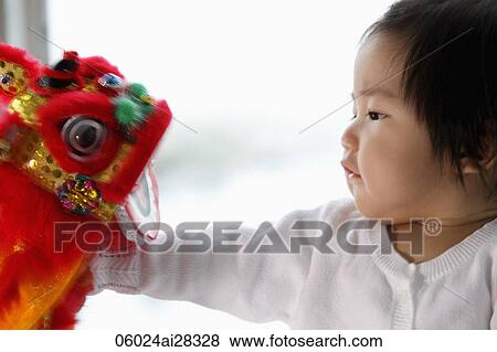Stock Photo - profile of baby looking at Chinese dragon toy. Fotosearch