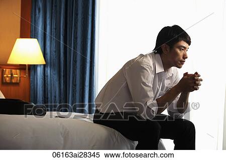 Profile of man sitting on the bed in hotel room View Large Photo Image Stock Photography - Profile of man sitting on the bed in hotel room. Fotosearch