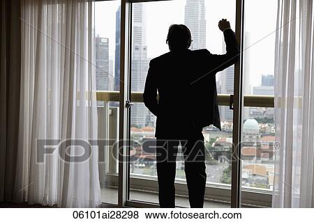 Rear view of business man looking out of window at buildings View Large Photo Image Stock Photo - Rear view of business man looking out of window at buildings. Fotosearch