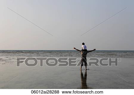 Son sitting on father's shoulders looking at the sea View Large Photo Image Stock Photo - Son sitting on father's shoulders looking at the sea. Fotosearch