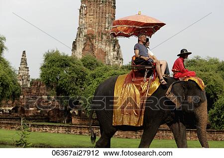 Stock Image - tourist riding a elephant in front of stone Wat at Ayutthaya, Thailand. Fotosearch