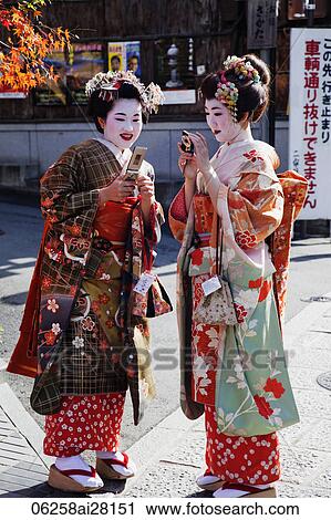 Two Geishas dressed in Kimonos looking at cell phones. View Large Photo Image Stock Image - Two Geishas dressed in Kimonos looking at cell phones.. Fotosearch