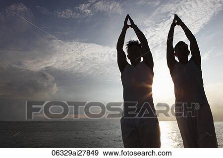 two men backlit doing yoga near water View Large Photo Image Stock Photo - two men backlit doing yoga near water. Fotosearch
