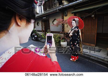 Woman taking photo of Geisha dressed up in traditional Japanese clothes View Large Photo Image Picture - Woman taking photo of Geisha dressed up in traditional Japanese clothes. Fotosearch