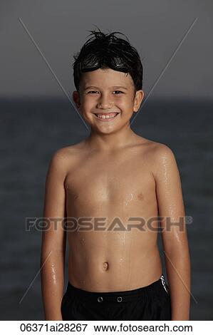 Young boy smiling in front of ocean with goggles on his head View Large Photo Image Stock Photo - Young boy smiling in front of ocean with goggles on his head. Fotosearch