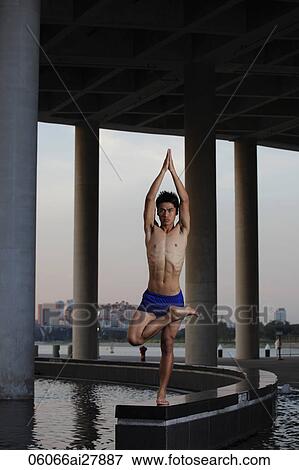 YOung man doing yoga under building View Large Photo Image Stock Photo - YOung man doing yoga under building. Fotosearch