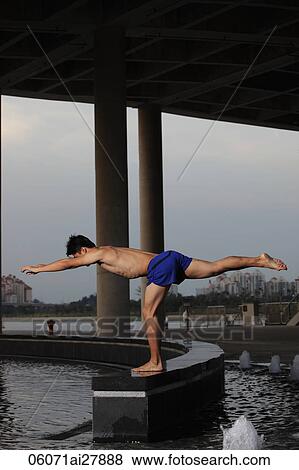 Young man doing yoga under building View Large Photo Image Stock Photo - Young man doing yoga under building. Fotosearch