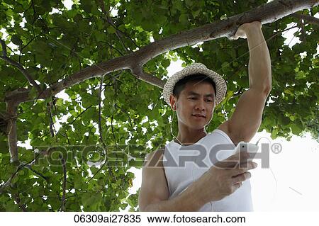 Young man holding phone and listening to music View Large Photo Image Stock Photography - Young man holding phone and listening to music. Fotosearch