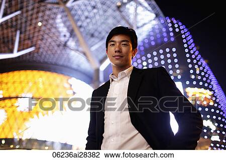 Young man in suit in front of lit building at night View Large Photo Image Stock Image - Young man in suit in front of lit building at night. Fotosearch