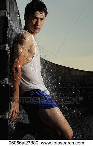 Stock Image - Young man leaning against water fountain. Fotosearch