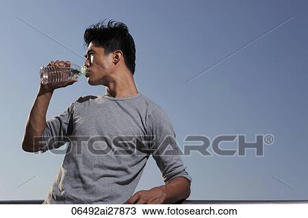 Young man leaning on wall drinking water View Large Photo Image Stock Image - Young man leaning on wall drinking water. Fotosearch