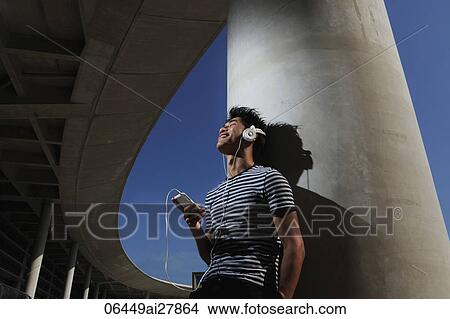 Young man listening to music and smiling View Large Photo Image Picture - Young man listening to music and smiling. Fotosearch