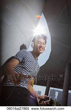 Young man listening to music with sunburst behind his head View Large Photo Image Stock Photography - Young man listening to music with sunburst behind his head. Fotosearch