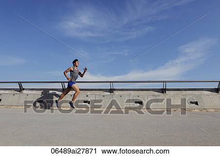 Stock Image - Young man running near wall. Fotosearch