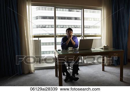 Young man sitting at desk with lap top looking stressed View Large Photo Image Stock Photo - Young man sitting at desk with lap top looking stressed. Fotosearch