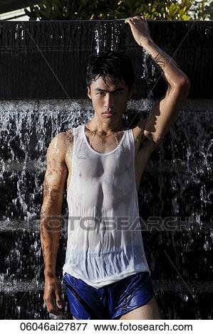 Stock Photo - Young man standing in water fountain. Fotosearch