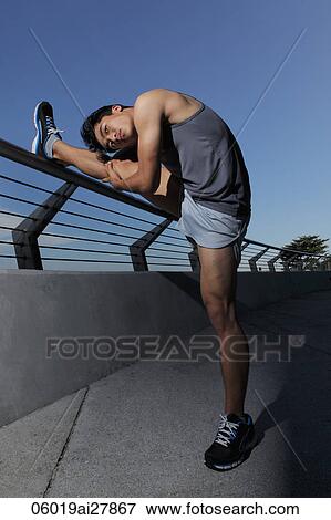 Young man stretching his leg on fence View Large Photo Image Stock Photo - Young man stretching his leg on fence. Fotosearch