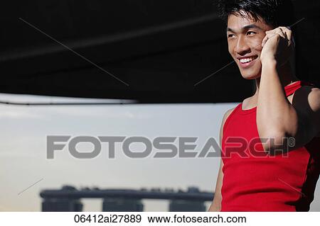Young man talking on phone and smiling View Large Photo Image Stock Photo - Young man talking on phone and smiling. Fotosearch