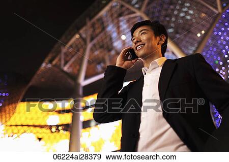 Stock Photo - young man talking on phone smiling at night. Fotosearch