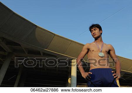 Stock Photograph - Young man wearing gold medals standing in front of building. Fotosearch