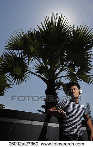 Stock Image - Young man wearing head phones, listening to music. Fotosearch
