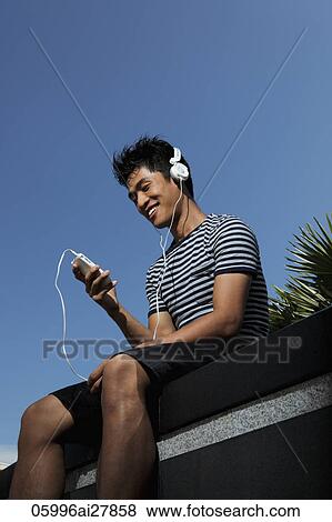 Young man wearing headphones and listening to music View Large Photo Image Stock Photo - Young man wearing headphones and listening to music. Fotosearch