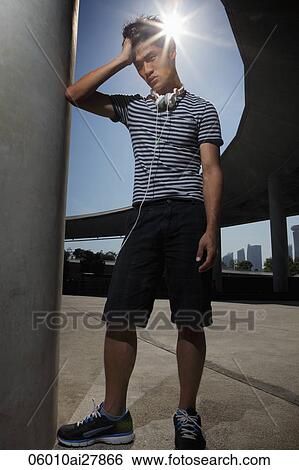 Young man with headphones with sunburst behind head View Large Photo Image Stock Photograph - Young man with headphones with sunburst behind head. Fotosearch