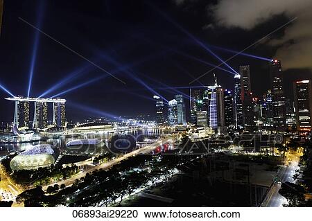 Stock Image - Buildings surrounding Marina Bay at night with light lasers from the Sands Casino, Singapore. Fotosearch