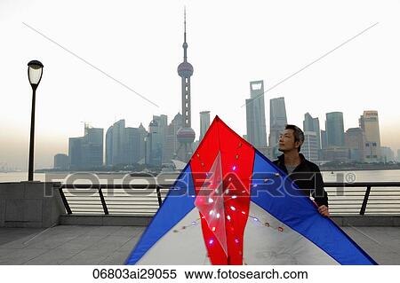 Stock Photography - Chines man holding large kite with the skyline of Shanghai in background. Fotosearch