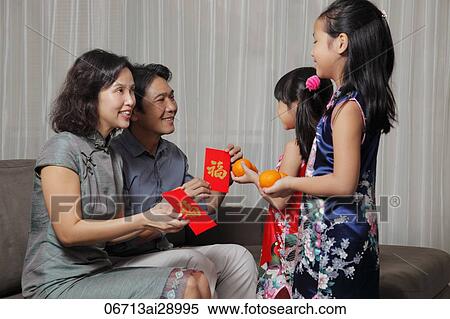 Chinese parents giving red envelopes (Hong Bao) to their daughters during Chinese New Year View Large Photo Image Stock Photography - Chinese parents giving red envelopes (Hong Bao) to their daughters during Chinese New Year. Fotosearch