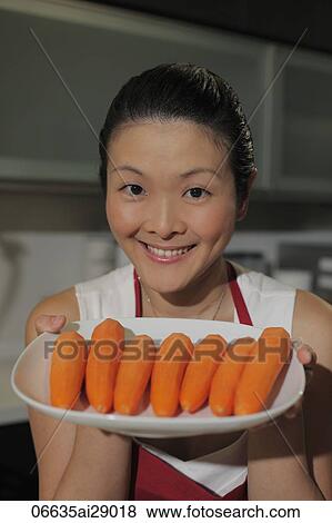 Chinese woman holding a plate of carrots and smiling View Large Photo Image Stock Photo - Chinese woman holding a plate of carrots and smiling. Fotosearch