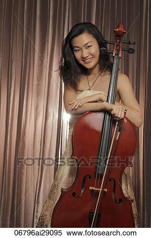 Stock Photography - Chinese woman standing with her cello and smiling. Fotosearch