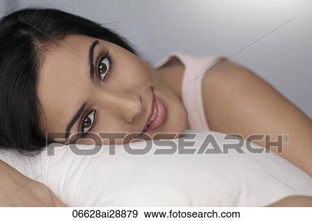 Close up of young woman resting on pillow looking at camera View Large Photo Image Stock Photo - Close up of young woman resting on pillow looking at camera. Fotosearch