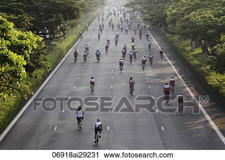 Stock Image - Cyclist riding down the road during a bike race. Fotosearch
