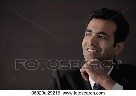 Stock Photography - Head shot of young man with hand on his chin smiling. Fotosearch