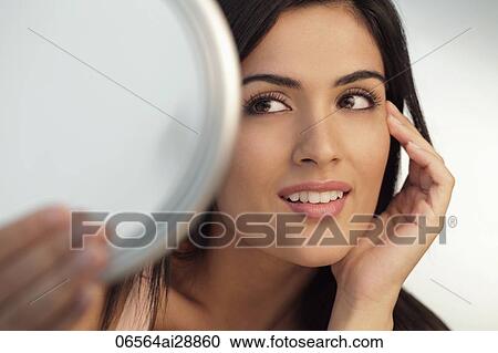 Head shot of young woman holding mirror and touching her face View Large Photo Image Stock Image - Head shot of young woman holding mirror and touching her face. Fotosearch