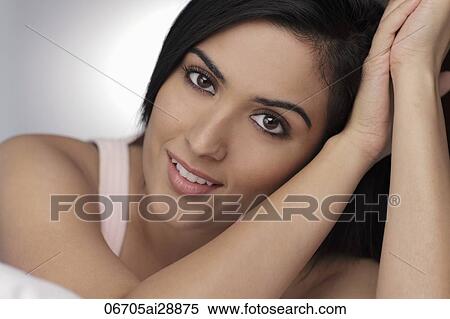 Stock Photography - Head shot of young woman smiling, resting on arms. Fotosearch