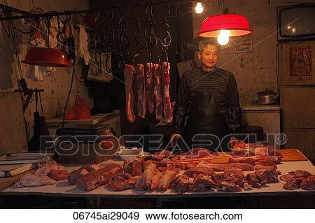 Stock Photo - Man selling meat in shop at night, Shanghai, China. Fotosearch