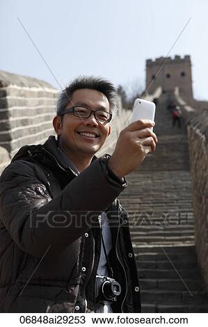 Stock Image - Man taking a photo with his phone on The Great Wall, China. Fotosearch