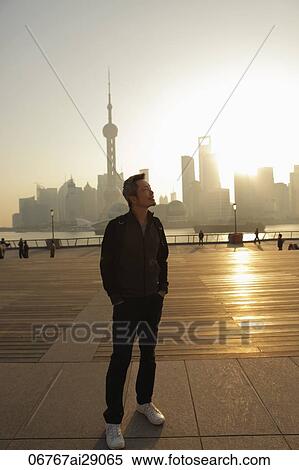 Mature man standing in front of city skyline at sunrise and smiling, Shanghai, China View Large Photo Image Stock Photography - Mature man standing in front of city skyline at sunrise and smiling, Shanghai, China. Fotosearch