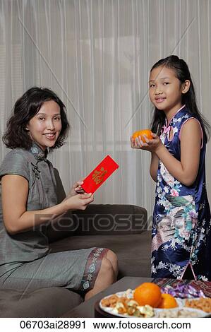 Mother giving daughter a red envelope (Hong Bao) during Chinese New Year View Large Photo Image Stock Image - Mother giving daughter a red envelope (Hong Bao) during Chinese New Year. Fotosearch