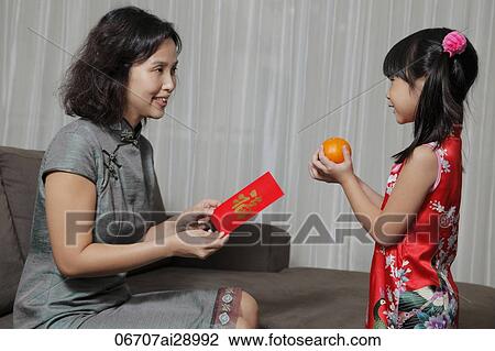 Mother giving daughter a red envelope(Hong Bao) while daughter gives two oranges View Large Photo Image Stock Image - Mother giving daughter a red envelope(Hong Bao) while daughter gives two oranges. Fotosearch