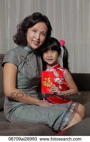 Stock Image - Mother holding daughter with red envelope (Hong Bao). Fotosearch