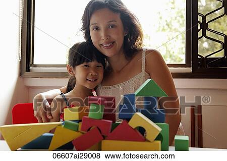 Mother hugging her young daughter and smiling, blocks in foreground View Large Photo Image Stock Photo - Mother hugging her young daughter and smiling, blocks in foreground. Fotosearch
