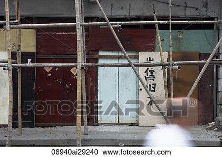 Stock Image - Old wall made of doors in Shanghai with bamboo scaffolding. Fotosearch