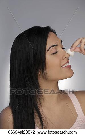 Stock Image - Profile of young woman cleaning her face with cotton ball. Fotosearch